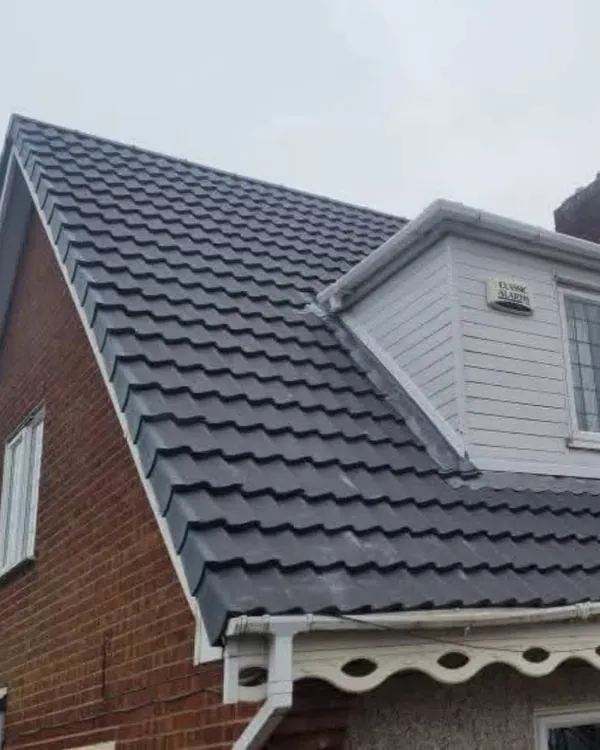 A red-brick house with a new dark grey tiled roof, a white-clad dormer with lead flashing along its side, and white fascia and guttering